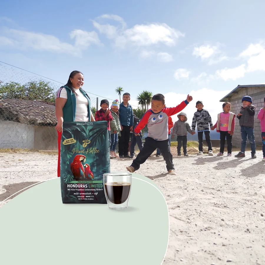 Frau und Kinder im Freien. Ein dunkelgrüner Beutel „Tchibo Privat Kaffee Honduras Limited“ mit Papageien und eine Kaffeetasse sind im Vordergrund. Ein Junge springt, andere Kinder stehen dahinter.