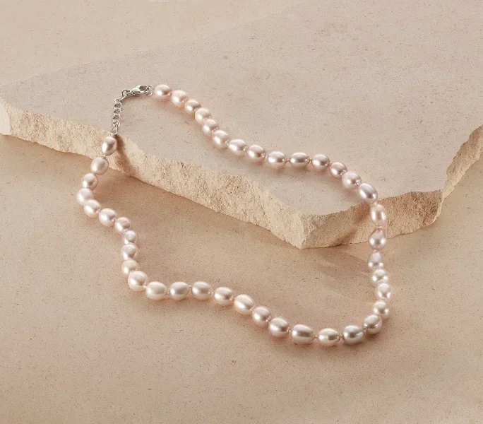 Eine 925 Silber Collier mit Süßwasserzuchtperlen liegt auf beigem Grund.