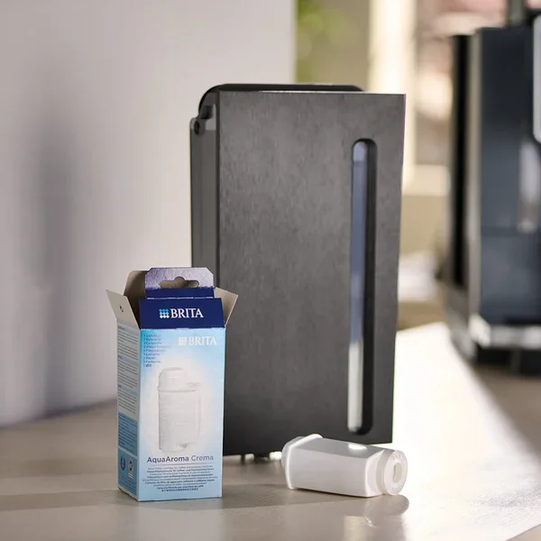 Eine Packung Brita AquaAroma Crema Filter neben einem Filter und einer Kaffeemaschine.