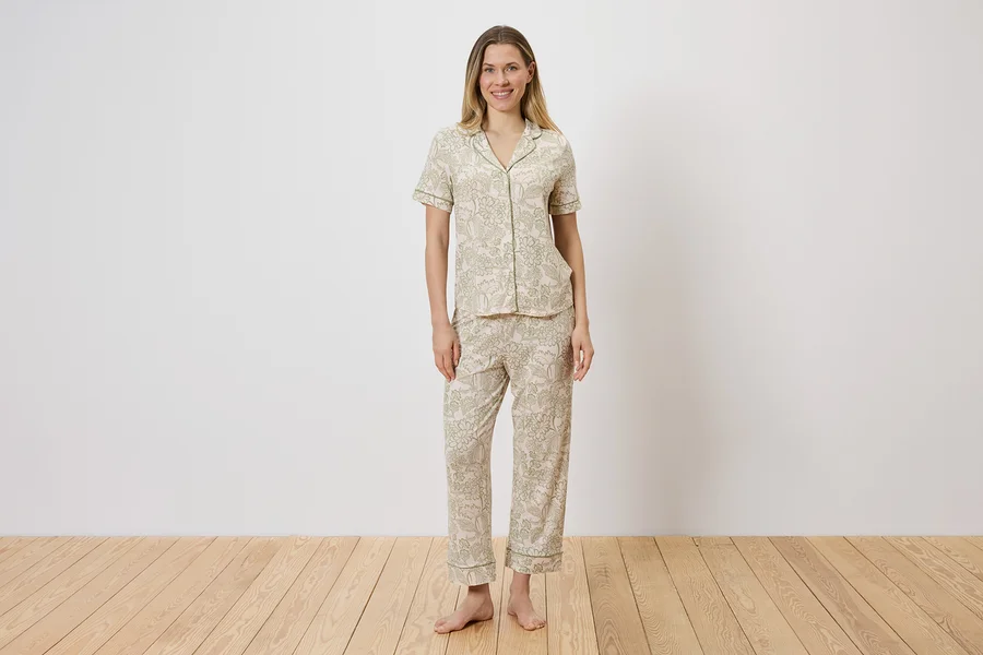 Frau in hell gemustertem Pyjama-Set aus Oberteil mit Knopfleiste und Hose.