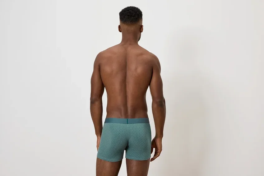 Ein Mann mit dem Rücken zur Kamera trägt grüne Boxershorts.