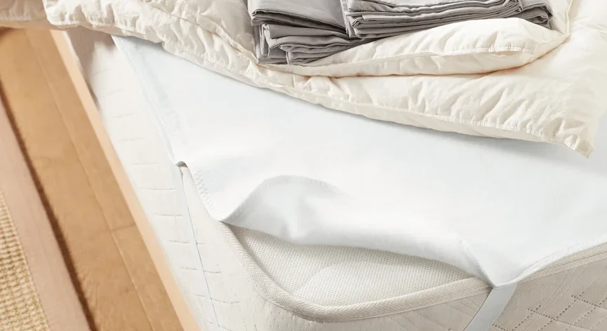 Bett mit Matratzenschoner, ca. 140 x 200 cm, Bettdecke und grauer Bettwäsche.