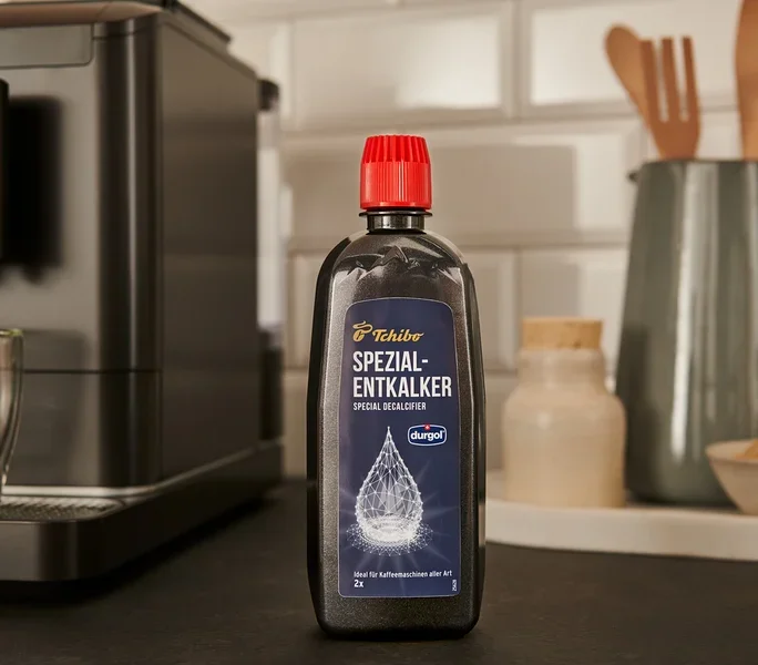 Eine schwarze Flasche durgol® Spezial-Entkalker, 400 ml, steht auf der Theke neben einer Kaffeemaschine.