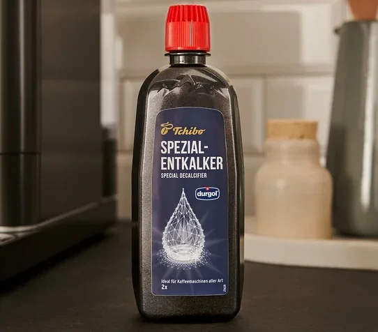 Eine schwarze Flasche durgol® Spezial-Entkalker, 400 ml, steht auf der Theke neben einer Kaffeemaschine.