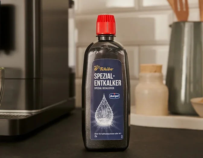Eine schwarze Flasche durgol® Spezial-Entkalker, 400 ml, steht auf der Theke neben einer Kaffeemaschine.