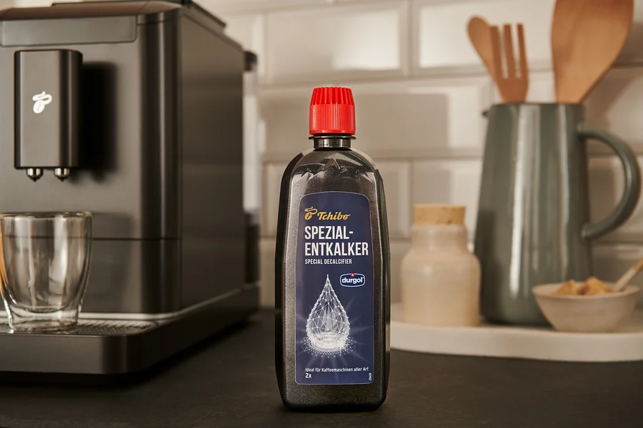 Eine schwarze Flasche durgol® Spezial-Entkalker, 400 ml, steht auf der Theke neben einer Kaffeemaschine.