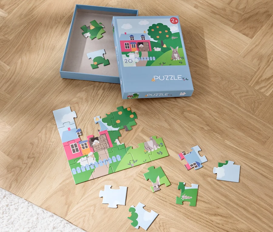 Ein teilweise zusammengesetztes Puzzle »Ostern« und eine Schachtel auf einem Holzboden.