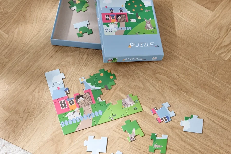 Ein teilweise zusammengesetztes Puzzle »Ostern« und eine Schachtel auf einem Holzboden.