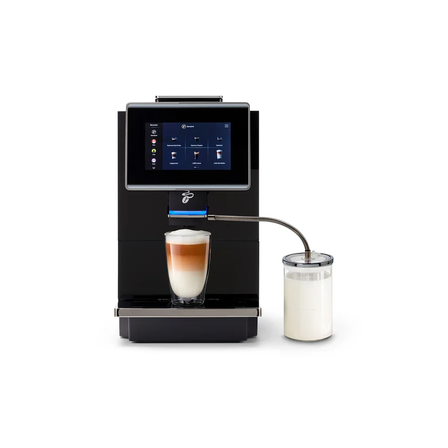 Ein schwarzer Kaffeevollautomat mit Touchscreen bereitet einen Latte Macchiato in einem Glas zu. Ein Milchbehälter ist seitlich angeschlossen.