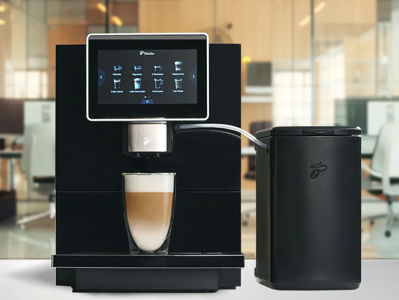 Schwarze Kaffeemaschine mit Touchscreen-Display, das Kaffeeoptionen zeigt, und einem Glas Latte Macchiato darunter. Daneben steht ein schwarzer Milchbehälter.