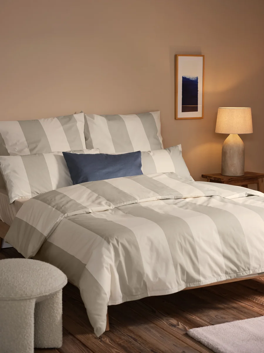 Schlafzimmer-Setup mit beige gestreifter Edelflanell-Bettwäsche, inklusive 2 Kopfkissenbezügen, 2 Dekokissen-Bezüge und Wohndecke.