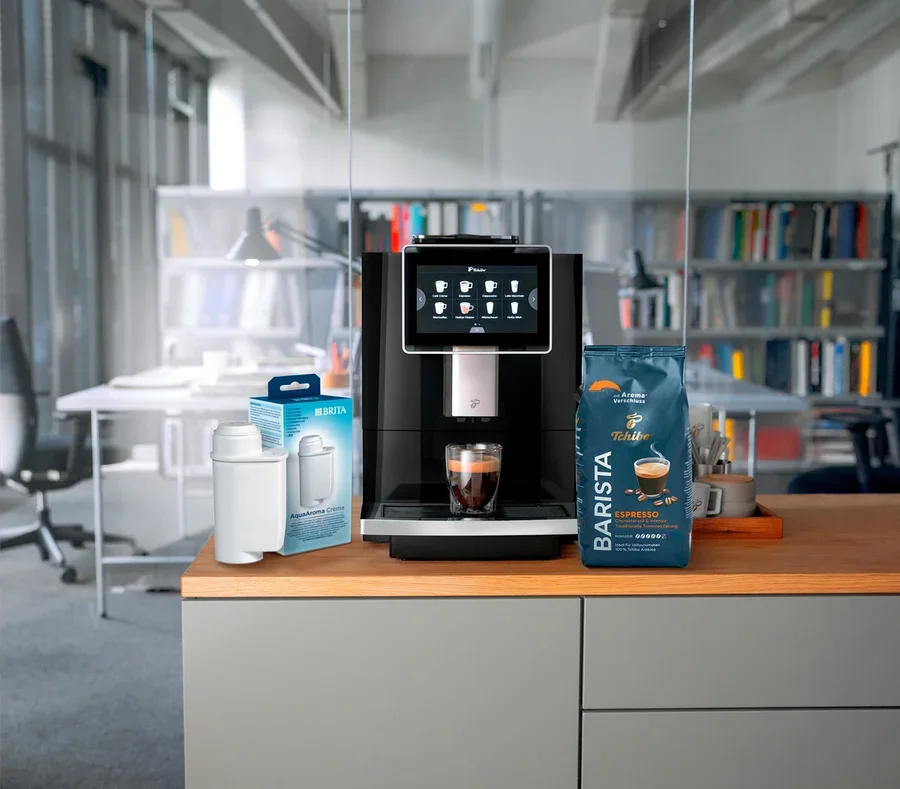 Auf einer Küchentheke stehen eine Kaffeemaschine, eine Packung Brita Wasserfilter und eine Packung Tchibo Barista Espresso.