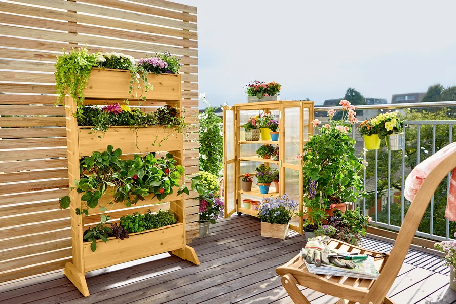 Holzregal mit Pflanzen auf einem Balkon.