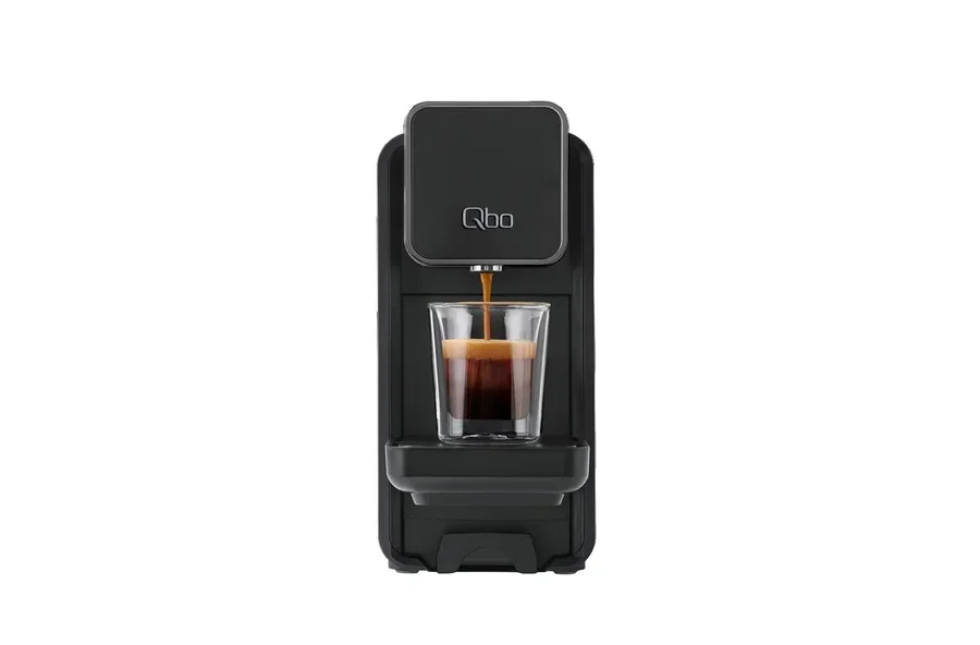 Espresso läuft aus einer schwarzen Qbo-Kaffeemaschine in ein Glas.