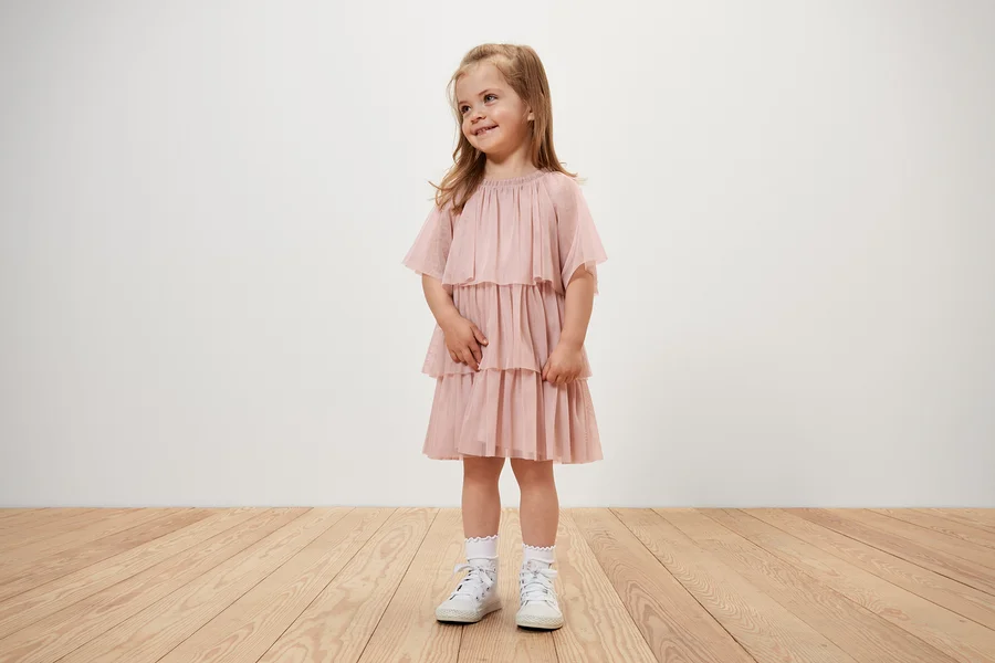Ein lächelndes Mädchen trägt ein Kinder-Tüllkleid.