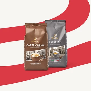 Zwei Tchibo Kaffeepackungen vor rot-weißem Hintergrund. Eine braune Packung "Caffè Crema Vollmundig" und eine graue Packung "Espresso Aromatisch".
