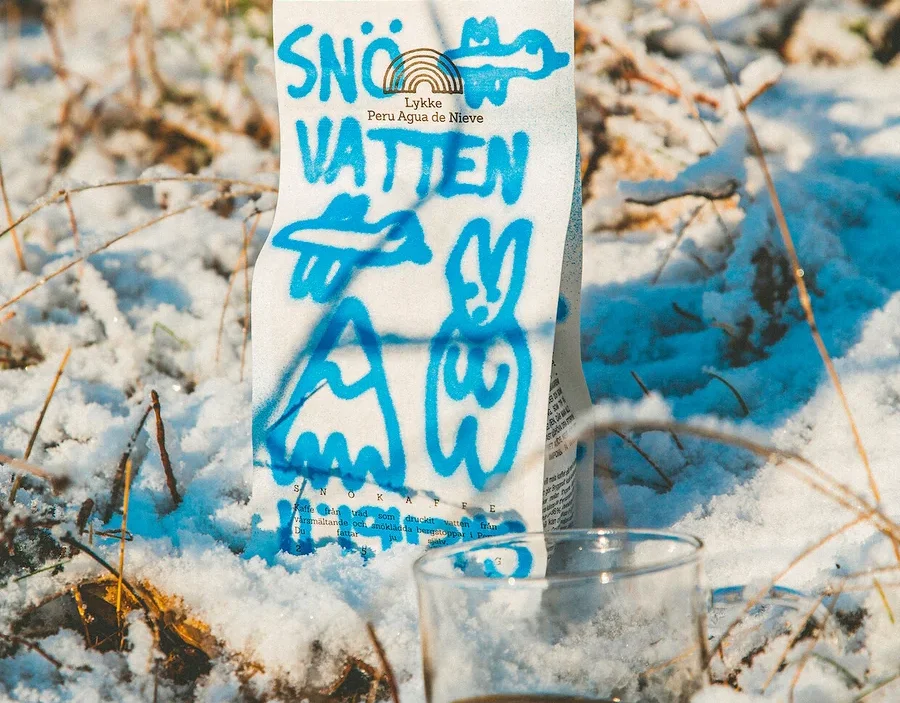 Eine Packung Lykke Peru Agua de Nieve Kaffee und ein Glas Kaffee stehen im Schnee.