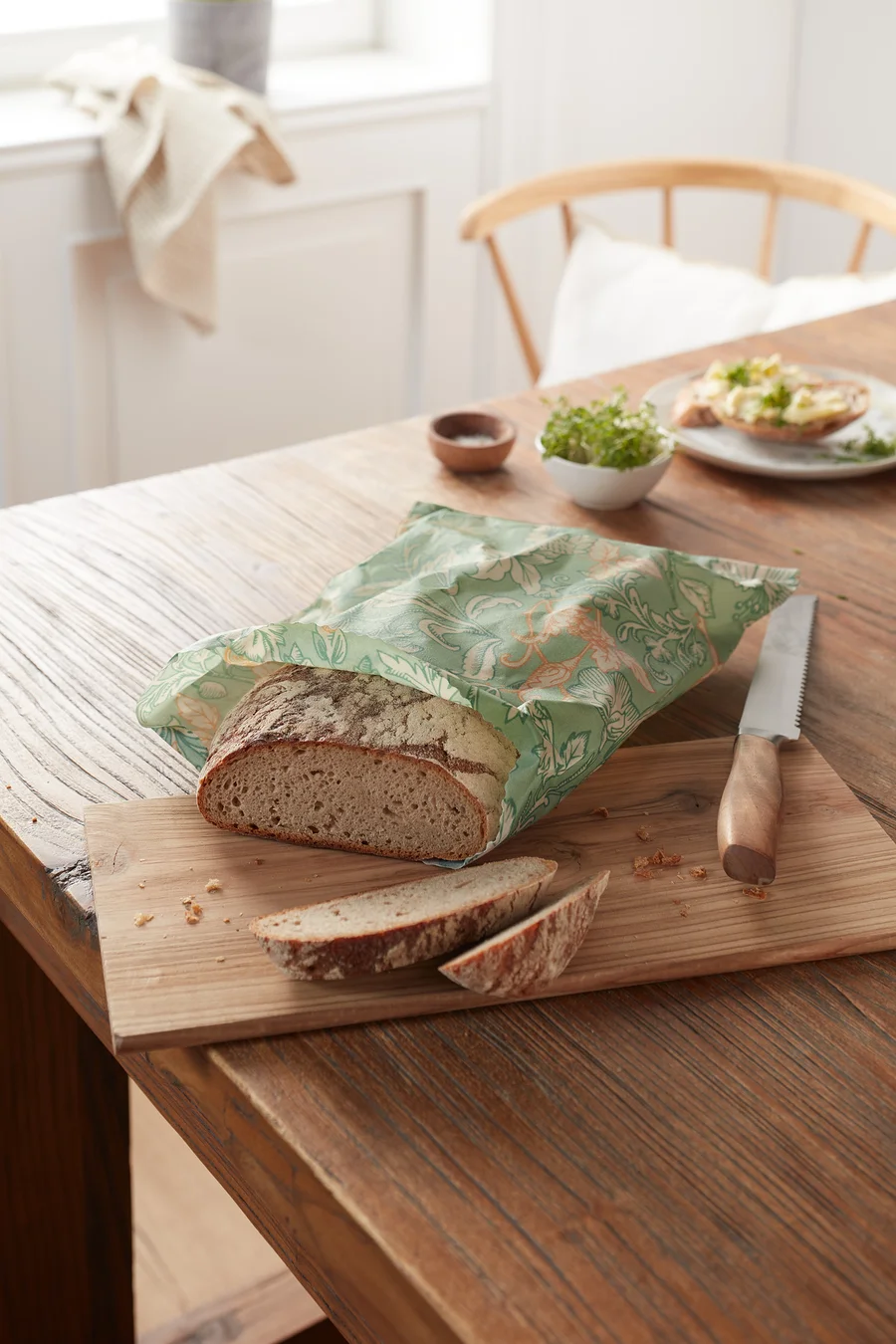 Brotlaib im Bienenwachs-Brotbeutel auf Holzbrett.