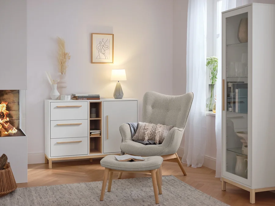 Tischleuchte mit Keramikfuß steht auf einer weißen Kommode im Wohnzimmer.