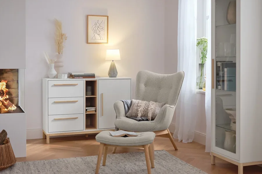 Tischleuchte mit Keramikfuß steht auf einer weißen Kommode im Wohnzimmer.