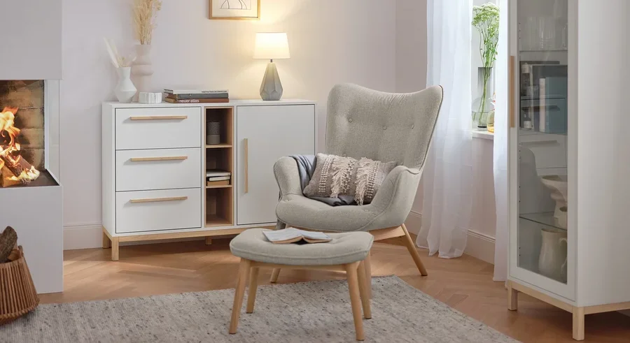 Tischleuchte mit Keramikfuß steht auf einer weißen Kommode im Wohnzimmer.