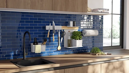 Küche mit Holzarbeitsplatte, schwarzem Spülbecken und Wasserhahn. Blaue Fliesenrückwand mit weißen Wandorganisatoren, Messern und Kräutern.