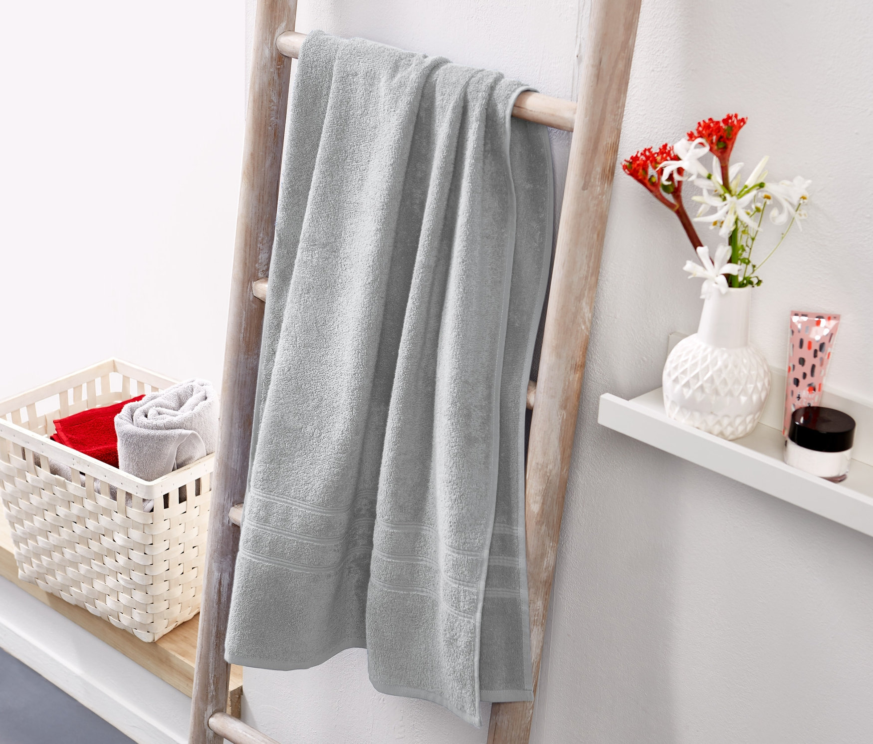 Graues Frottier-Badetuch hängt an einer Holzleiter.