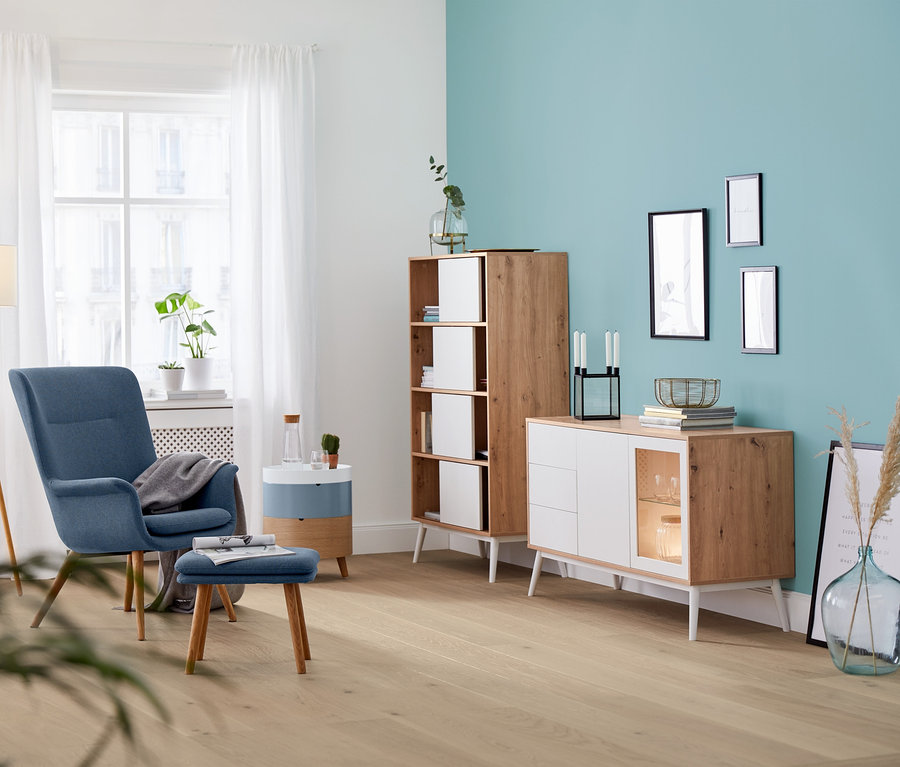 Wohnzimmer Interieur mit blauem Sessel, Lampe und rundem Beistelltisch mit Stauraum.