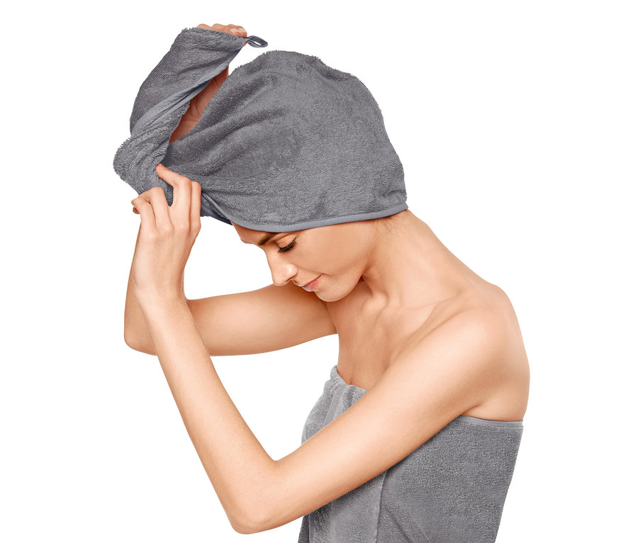 Frau legt ein graues Turban-Handtuch um ihr Haar.