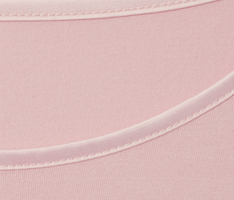 Nahaufnahme eines roséfarbenen Langarmshirts mit Satindetail am Ausschnitt.