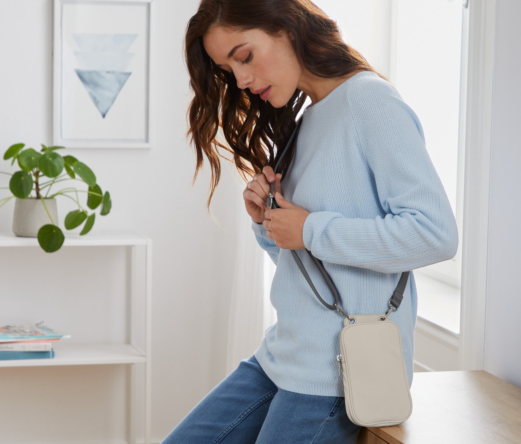 Frau justiert den Riemen einer Mini-Tasche.