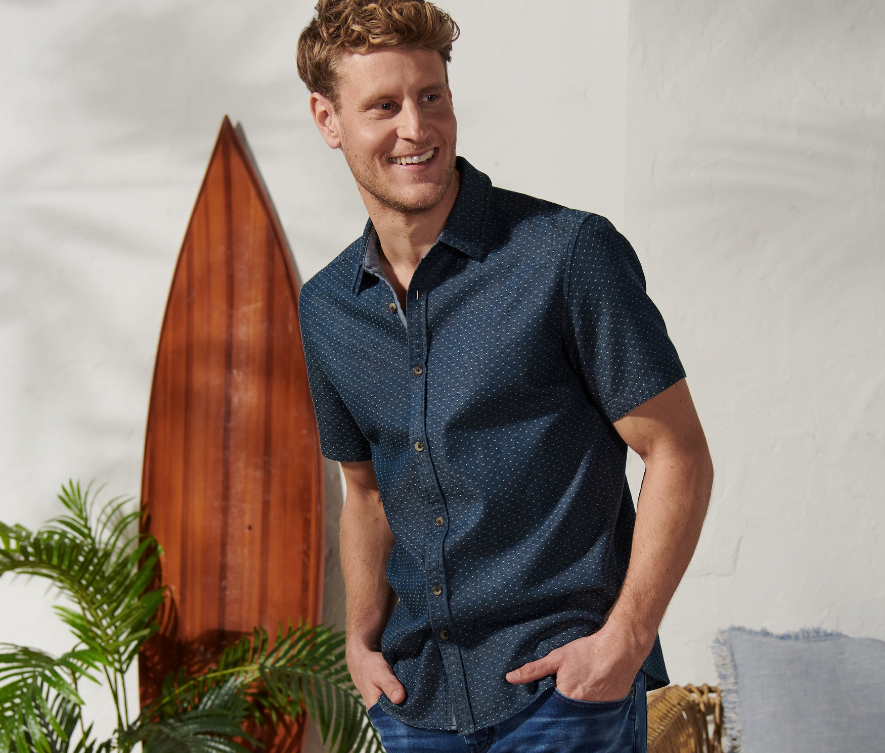 Mann mit Händen in den Hosentaschen posiert in Kurzarm-Hemd »Mustang« und Jeansshorts.