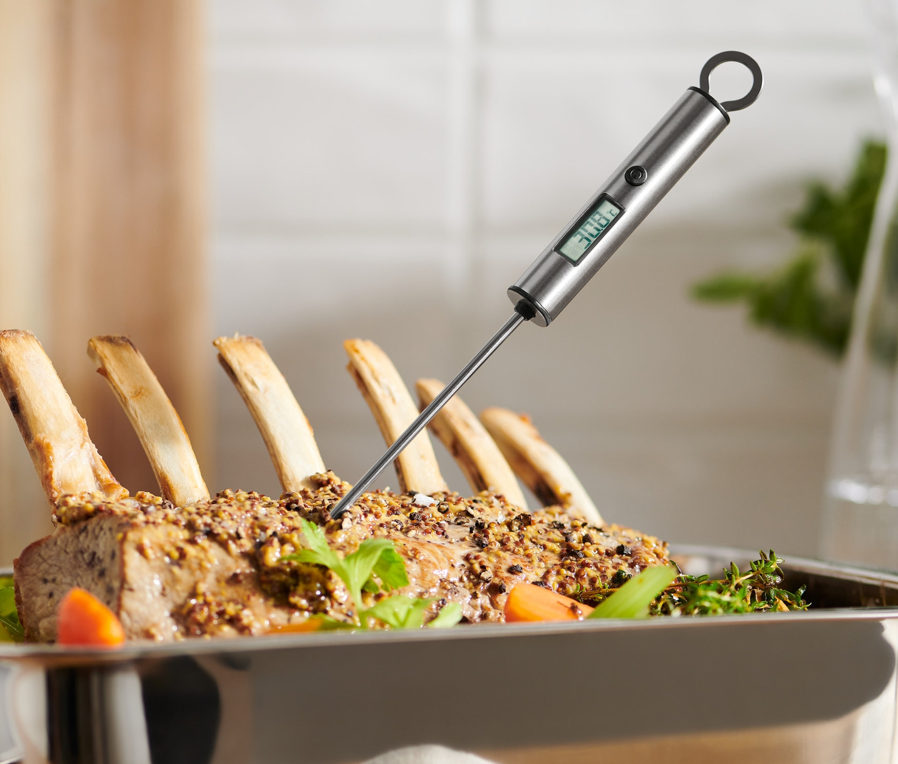 Digitales Bratenthermometer steckt in gebratenem Fleisch in einer Edelstahlpfanne.