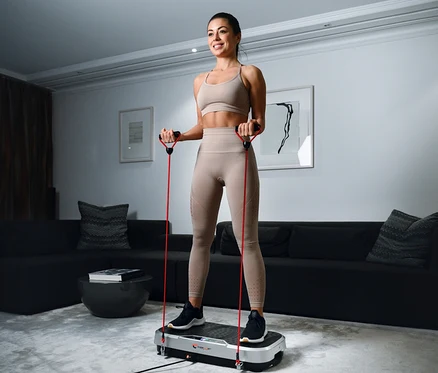 Frau trainiert mit Christopeit Vibrationstrainer Vibro VBT 4200 und roten Widerstandsbändern.