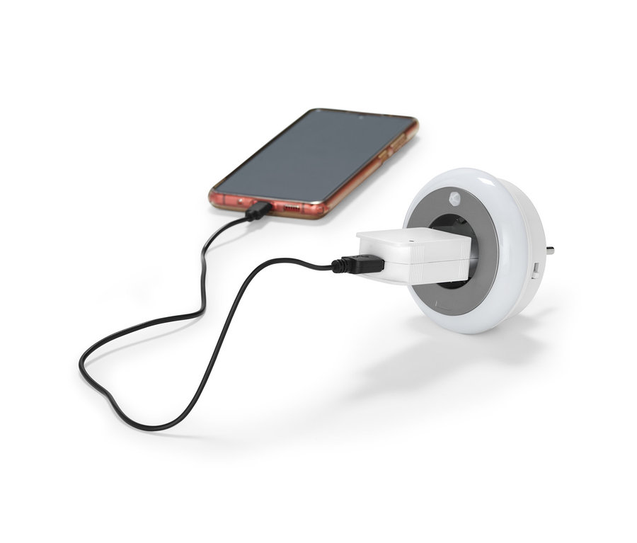 Handy wird mit LED-Nachtlicht mit Steckdose geladen.