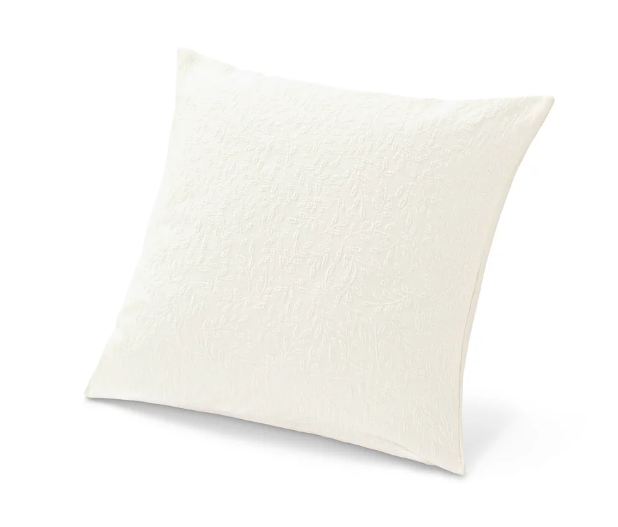 Ein beiger Dekokissen-Bezug mit Jacquard-Webung liegt auf einem weißen Untergrund.