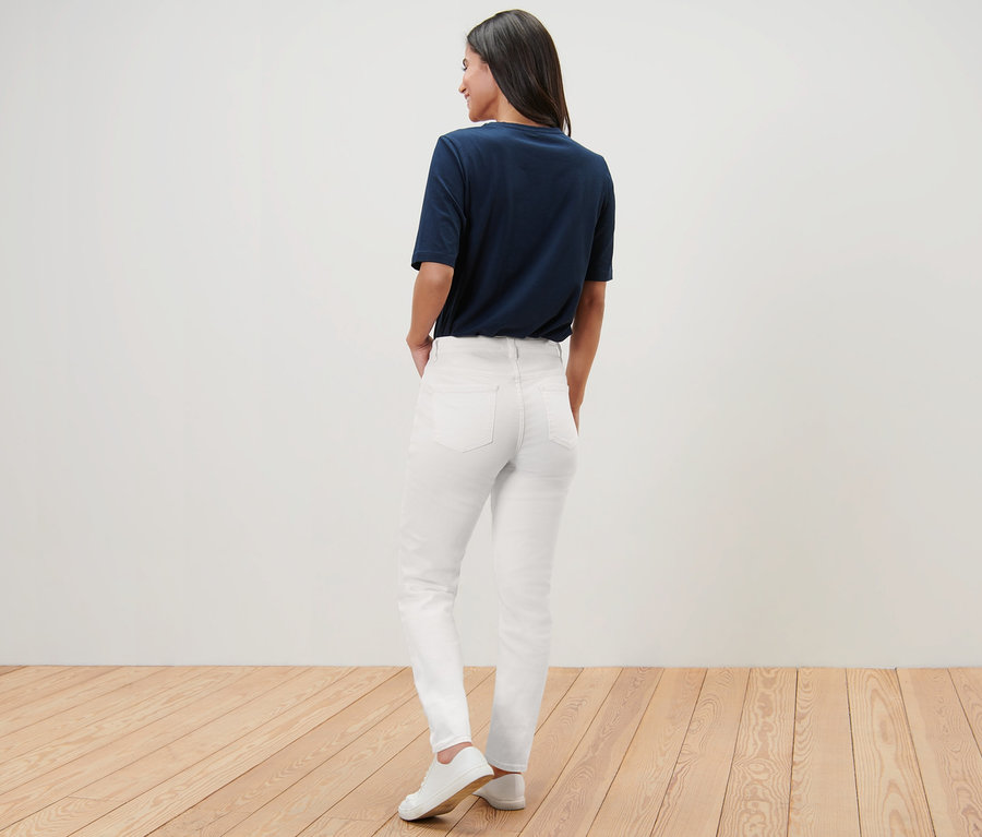 Frau posiert mit dem Rücken zur Kamera in Jeans – Fit »Kira«, T-Shirt und Turnschuhen.