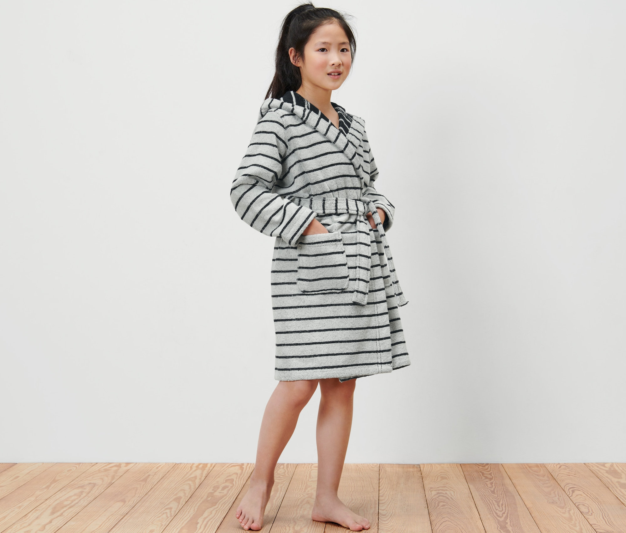 Mädchen trägt einen Kinder-Bademantel mit grauen und schwarzen Streifen.