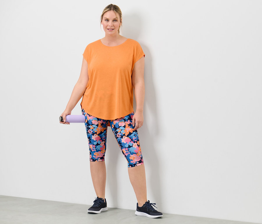 Frau hält eine lila Rolle und trägt ein pfirsichfarbenes Sportshirt.