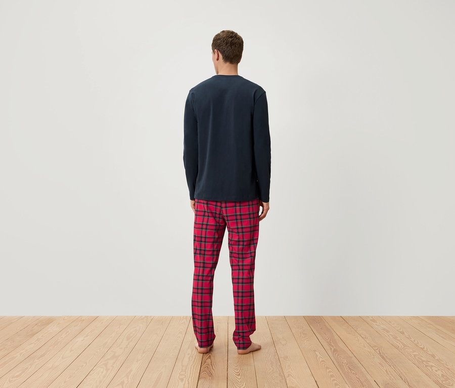 Mann von hinten trägt ein dunkelblaues langärmeliges Schlafshirt und eine rot karierte Schlafhose.