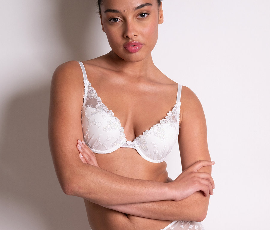 Frau posiert in weißem Spitzen-BH und Höschen. Sie trägt einen »White Nights« Push-Up-BH von Passionata.
