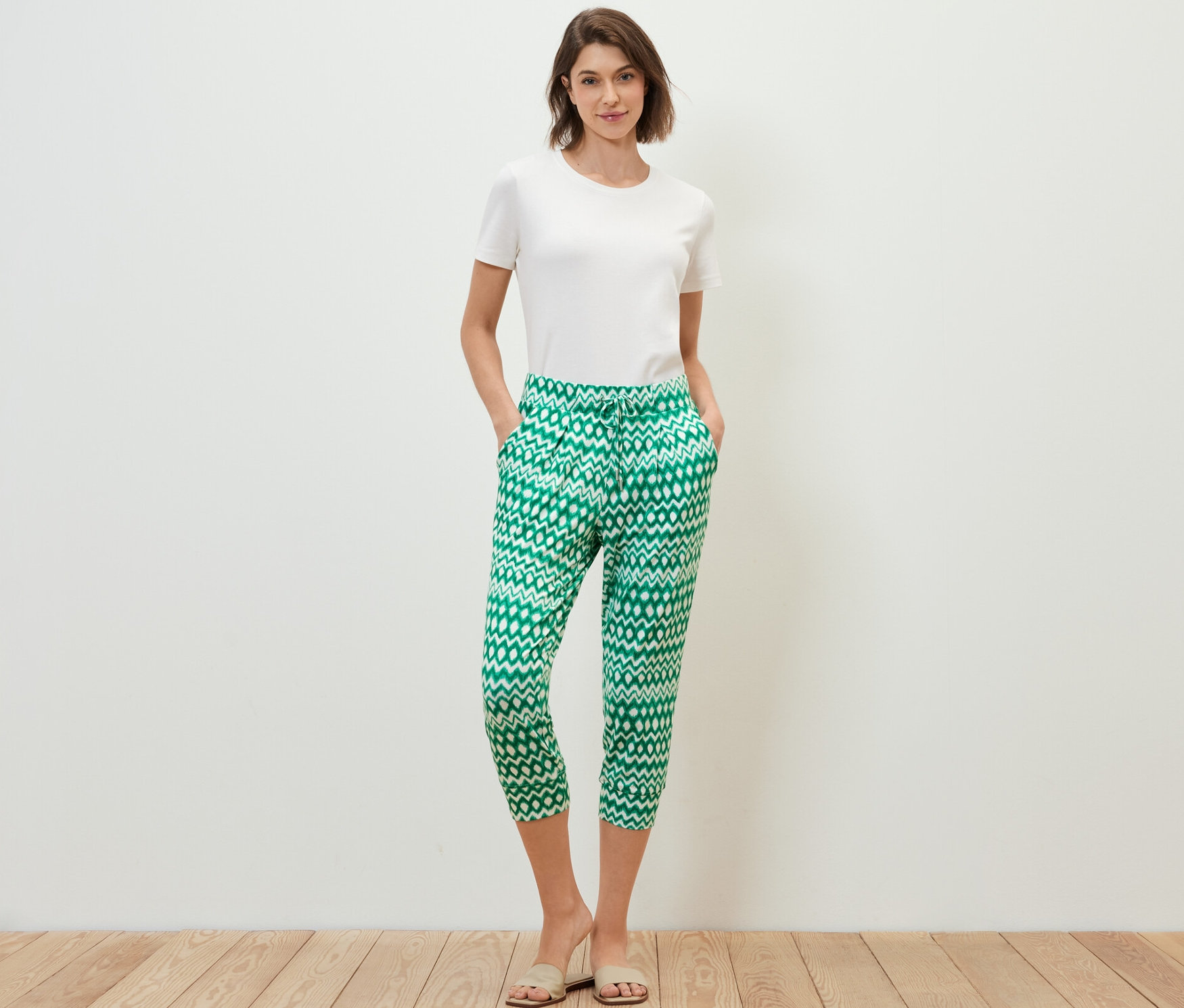 Frau steht mit Händen in den Taschen in einer bedruckten 3/4-Jerseyhose.