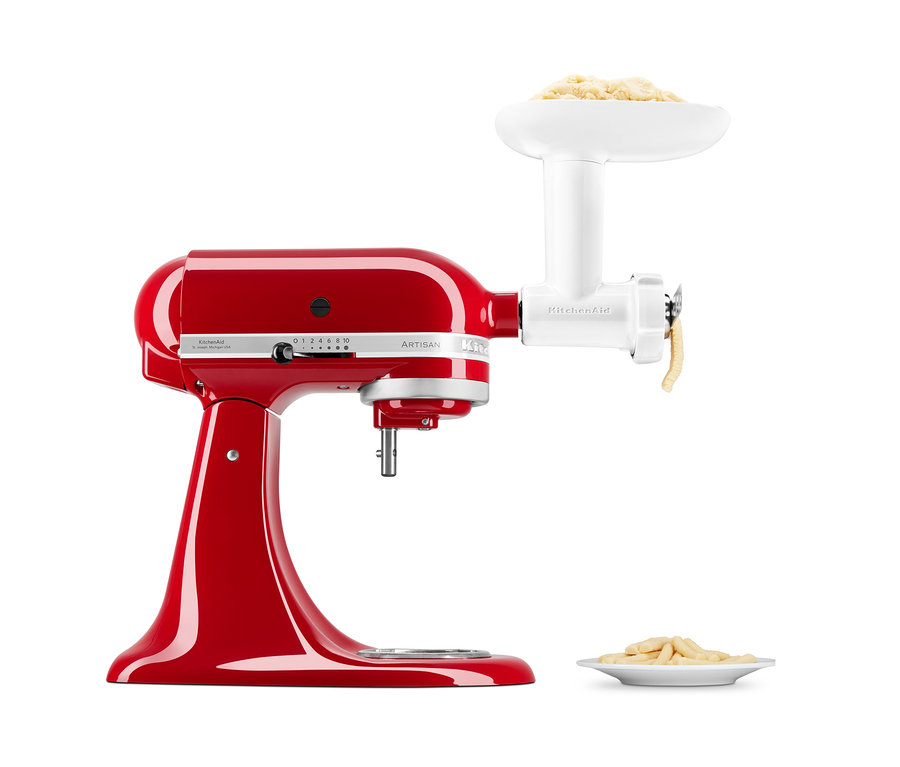 Rote KitchenAid ARTISAN Küchenmaschine mit weißem Spritzgebäckvorsatz und fertigen Keksen auf einem Teller.
