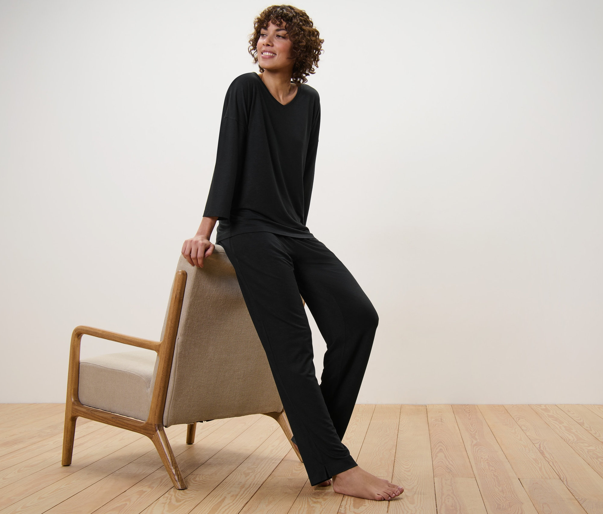 Frau sitzt in schwarzem Pyjama auf einem Sessel.