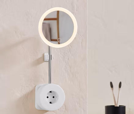 An der Wand ist eine Steckdose mit LED-Kosmetikspiegel.