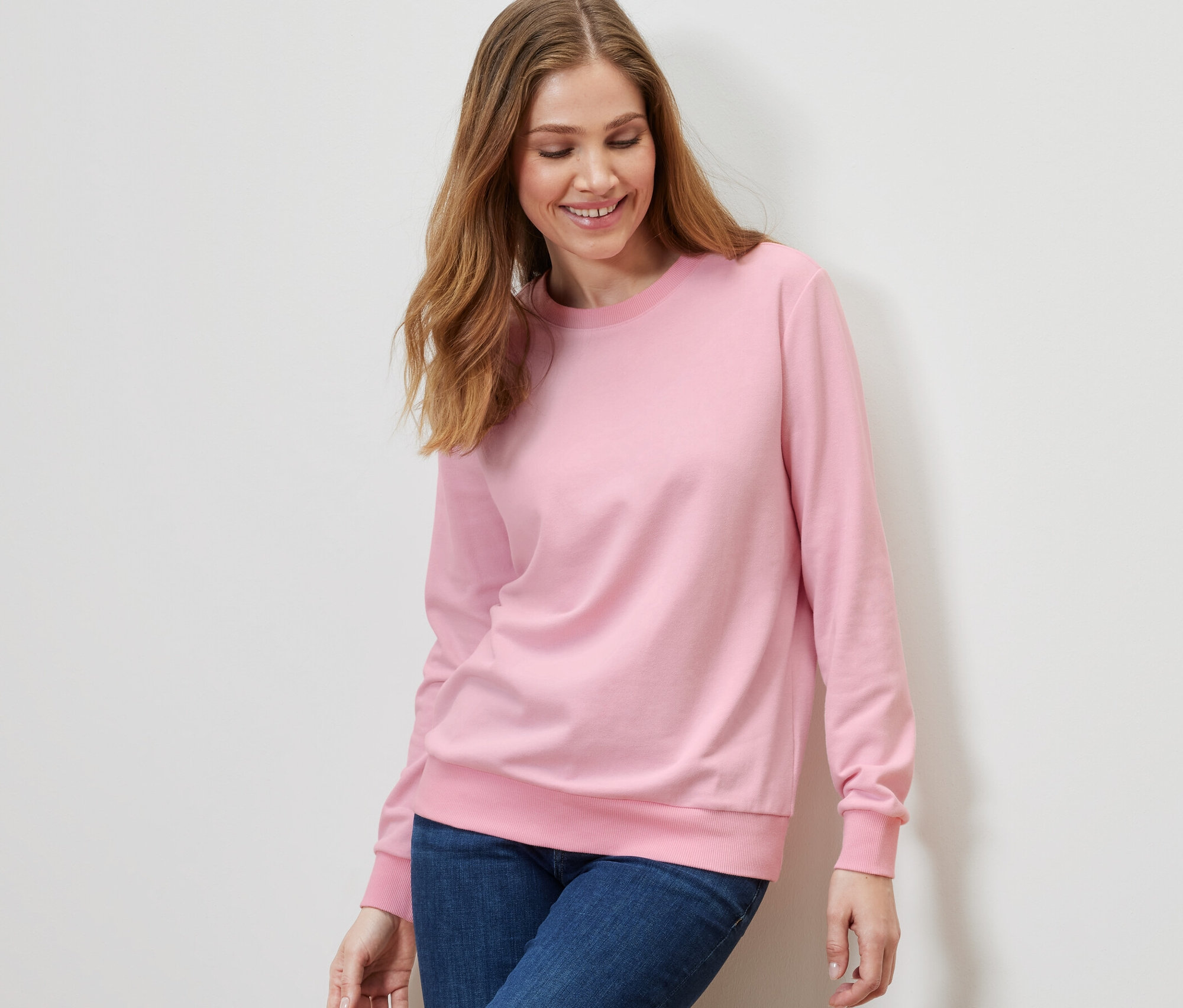 Frau trägt ein rosa Sweatshirt und Jeans.