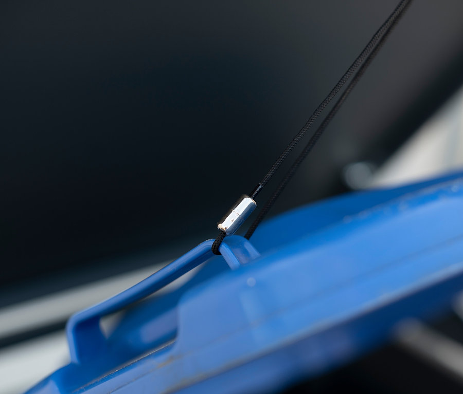 Detailansicht eines blauen Mülltonnendeckels mit schwarzer Kordel.
