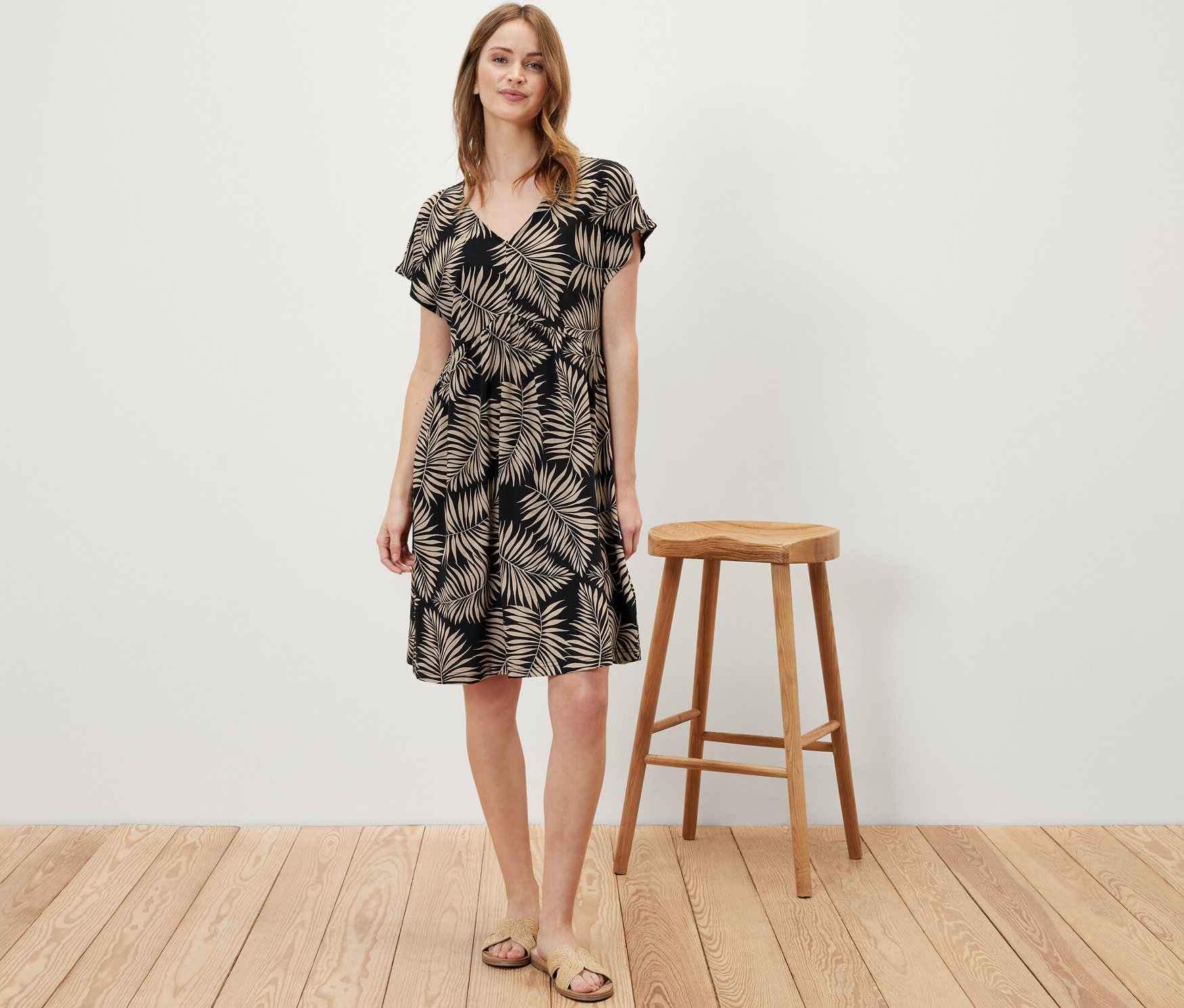 Frau steht und trägt ein bedrucktes Jerseykleid.