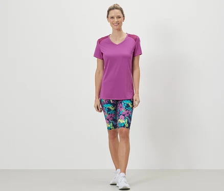 Frau trägt ein Sportshirt und geblümte Shorts.