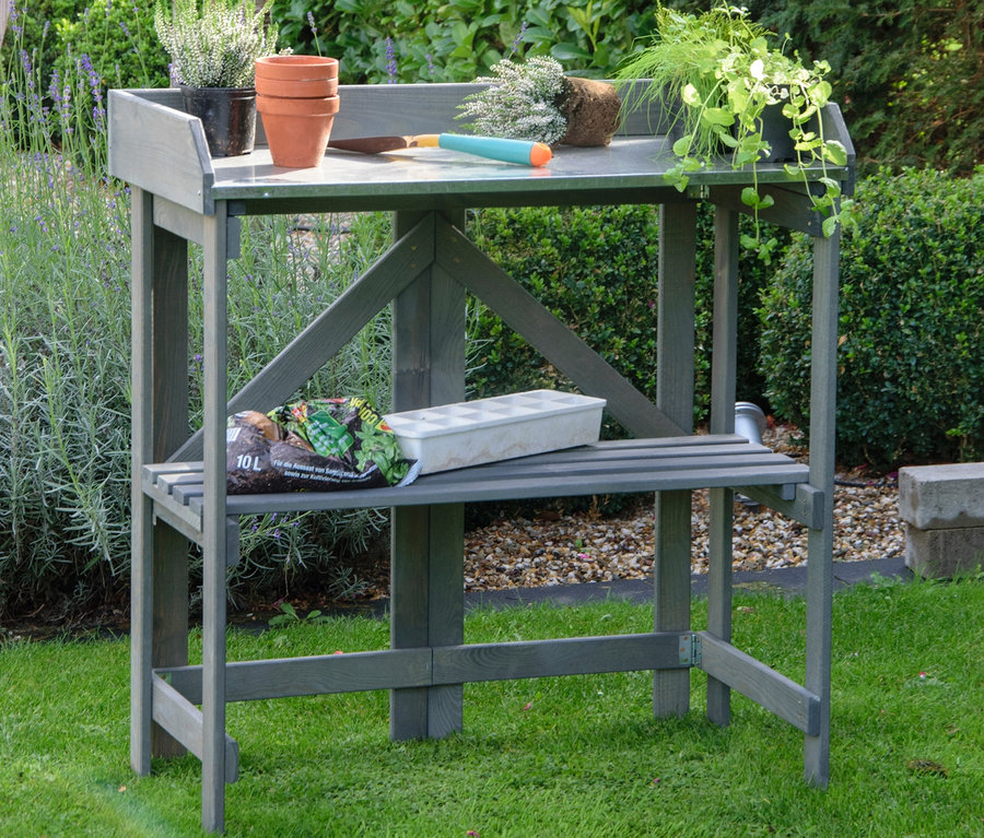 Grauer, klappbarer Pflanztisch mit Blumen, Blumentopf, Erde und Blumen im Garten.